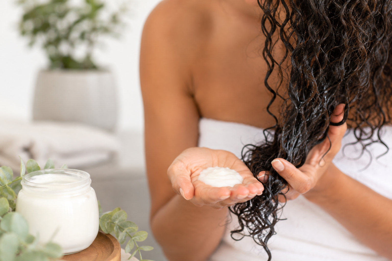 Close up of a woman applying deep conditioner to her curls.